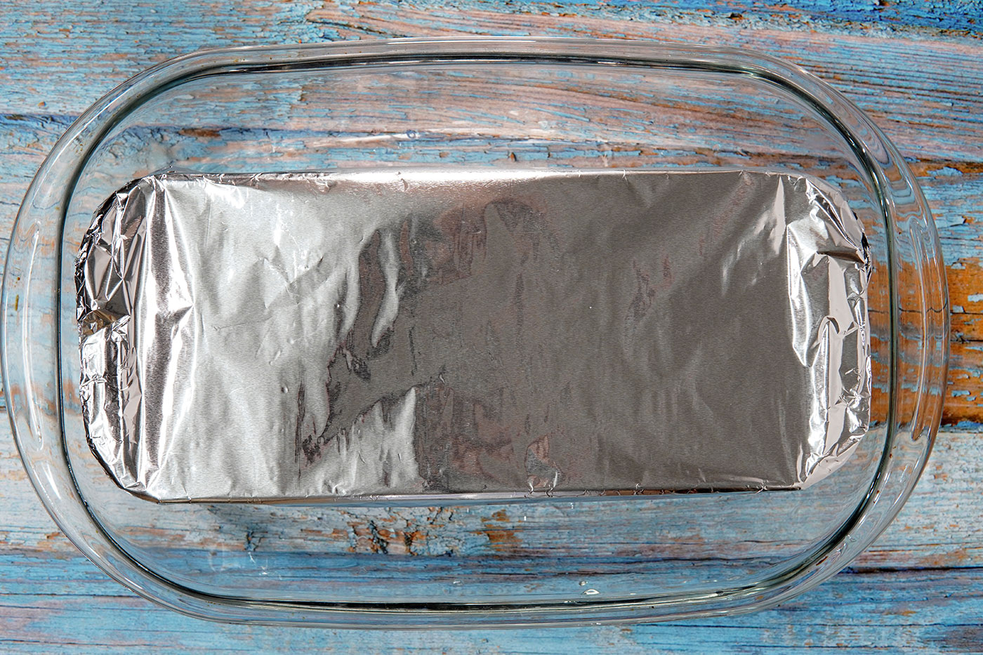 Molde del pudin de pan cubierto con papel de aluminio